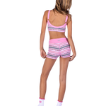 A woman shown from the back wearing a pink two-piece dance outfit with a geometric pattern, featuring a sports bra and matching shorts. The brand name 'XO' is printed on the back waistband of the shorts.