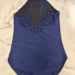 A royal blue halter-neck one-piece leotard with a floral cutout pattern across the chest, laid flat on a white marble surface.