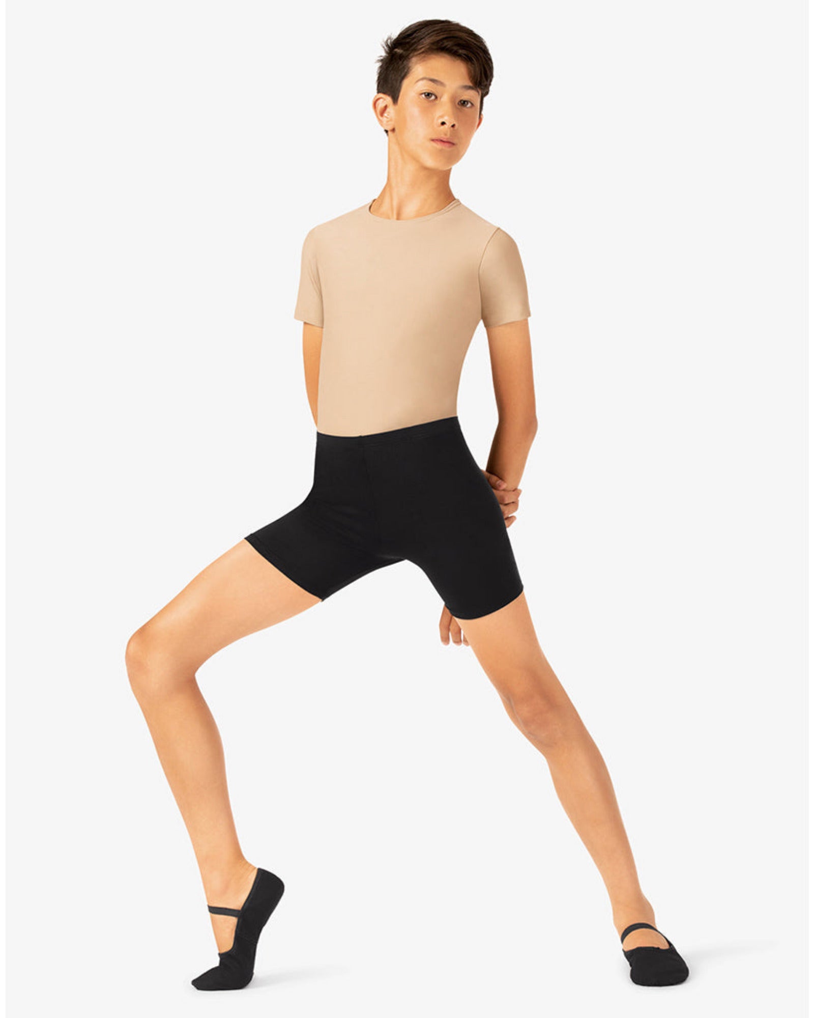 Person wearing a beige top and black shorts on a white background