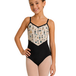 A young girl modeling a black leotard with a cream-colored patterned bodice featuring blue and gold ballet dancer illustrations, set against a plain white background.