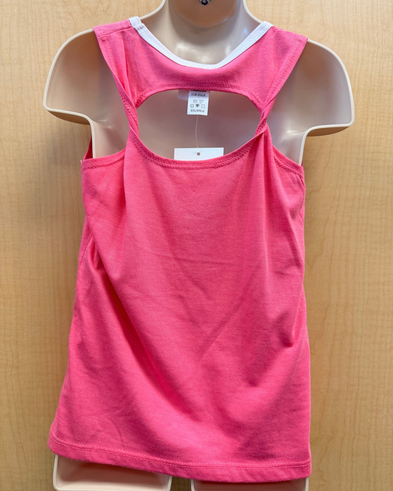 A bright pink sleeveless tank top displayed on a beige mannequin torso against a light wood background. The tank has a double-strap racerback design with a cutout at the upper back and a white inner collar trim.