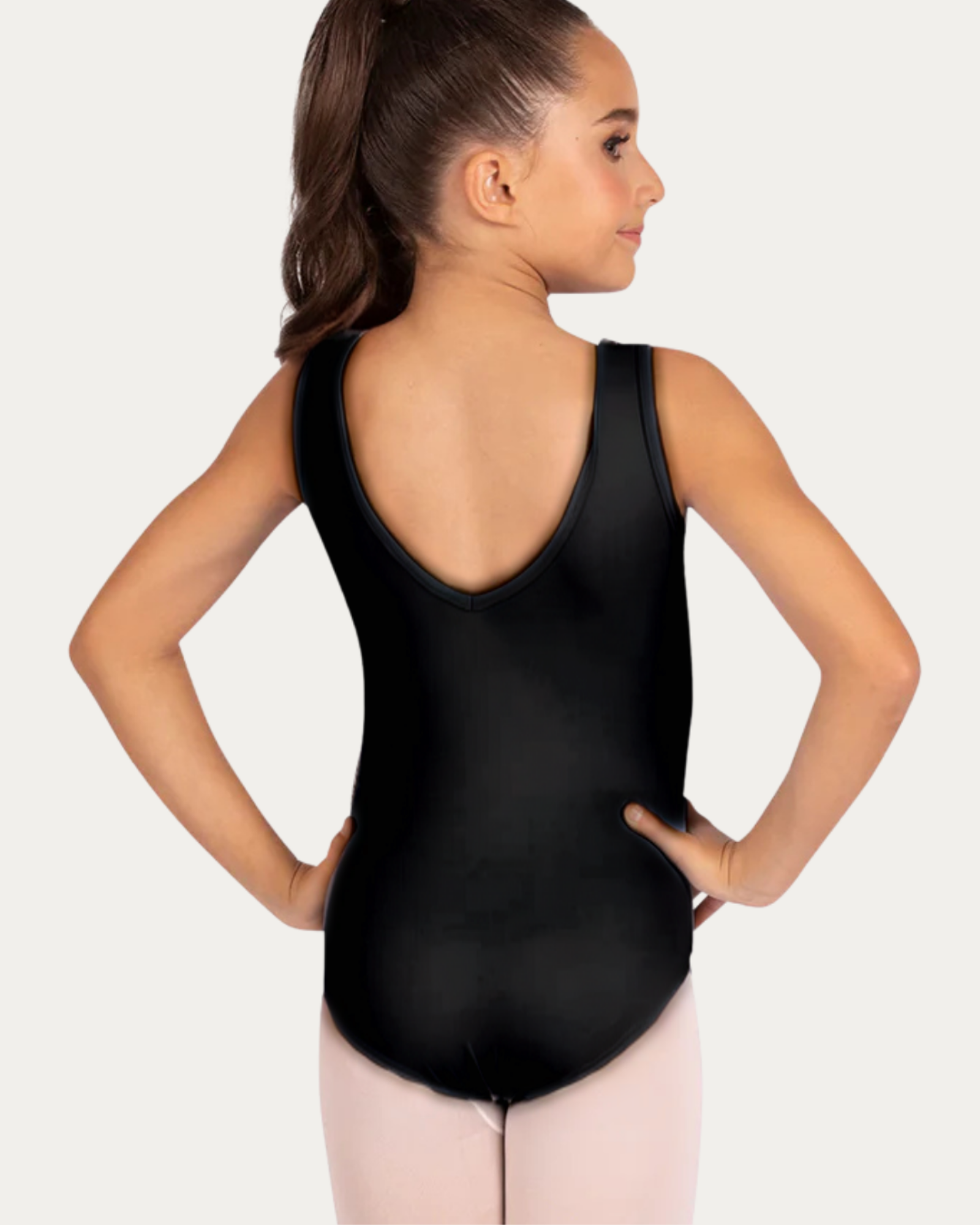 Young girl wearing a black leotard and pink tights on a white background