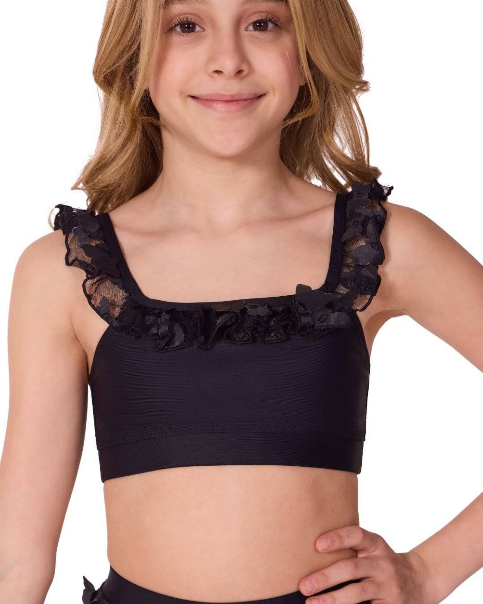 Young girl wearing a black crop top with ruffled details on a white background