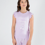 A young girl modeling a lavender pajama set with a ruffled sleeveless top and matching shorts. The top features a white graphic print that reads 'Tutu Sleepy' with a ballet shoe illustration.